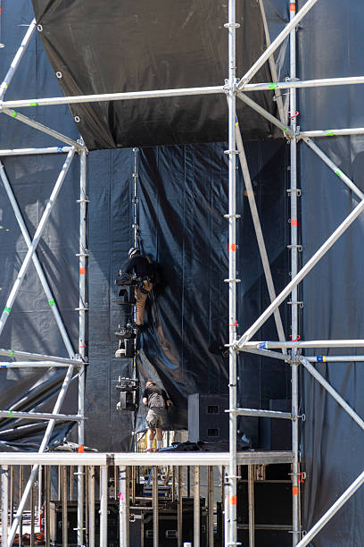 istock Workers setting up professional lighting equipment on an open-air stage 2230300777