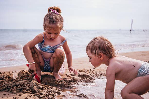 istock Two girls digging sand by the water 2230301798