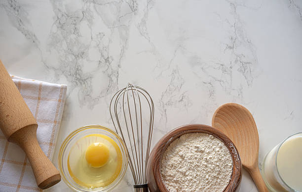 istock Baking preparation with flour, egg, and utensils on a marble countertop in a bright kitchen 2230301974
