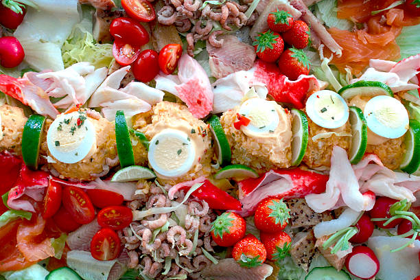 Fish salad with shrimps, tuna, smoked mackerel salmon and coalfish tomatoes, cucumber, corn, olives , eggs and onion on white stone background, top view.