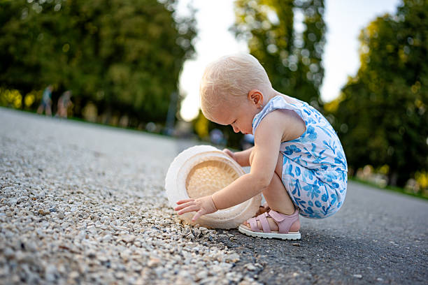 istock Child Collecting Pebbles in Sunlit Park 2230303253
