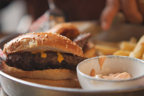 A cheeseburger with melted cheese and fries is served with dipping sauce.