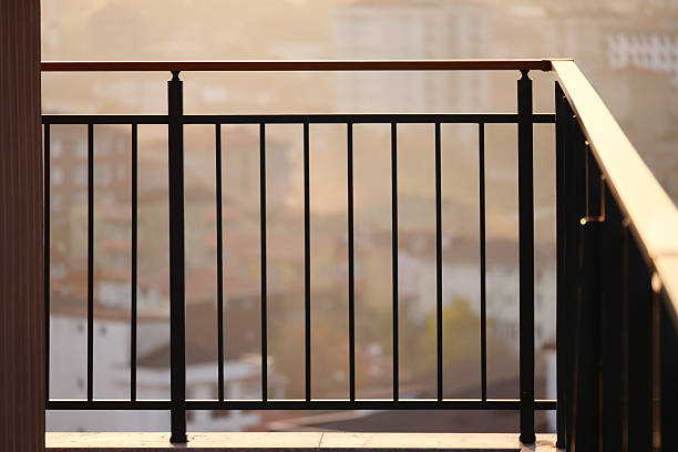 Sunset light casts a warm glow on a balcony railing with distant buildings.