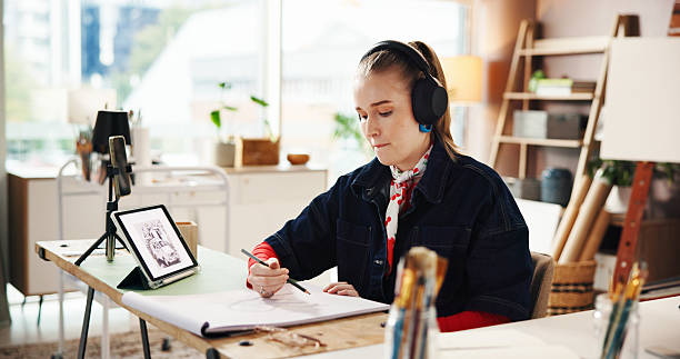 istock Drawing, tablet and headphones with woman in studio for art reference, illustration or sketch pad. Streaming, talent and inspiration with person and notebook in workshop for artist and creative hobby 2230309170