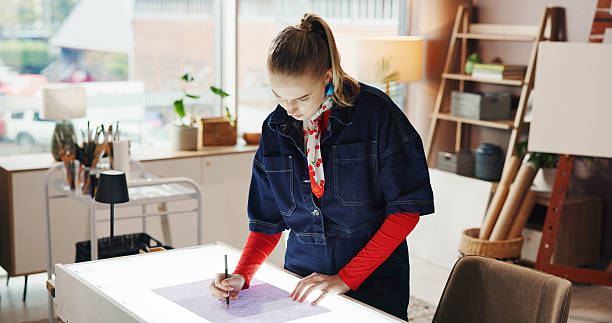 istock Drawing, illustration and light box with woman in studio apartment for remote work or sketch. Art, design and paper with freelance employee in home office for craft process or creative industry 2230309188