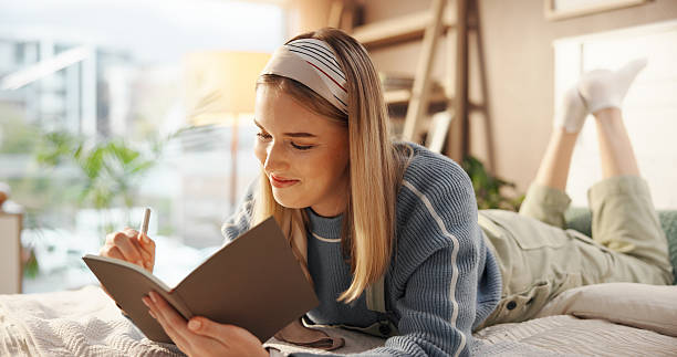 istock Woman, happy or writing in notebook on bed for article inspiration, plot development or remote work. Freelancer, writer and smile with diary in home for journal entry, project to do list and planning 2230317466