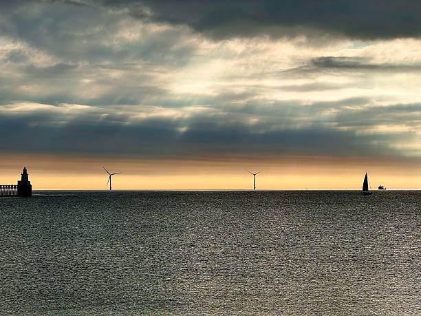 istock Dramatic orange cloudscape over the North Sea with Blyth lighthouse and wind turbines in silhouette in Northumberland 2230317931