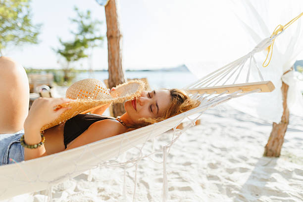 istock Young Woman Relaxing on Hammock by the Beach with Straw Hat 2230319267