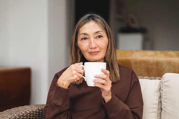 Woman enjoying a warm drink while seated in a cozy indoor setting during the afternoon, showcasing a moment of relaxation and reflection