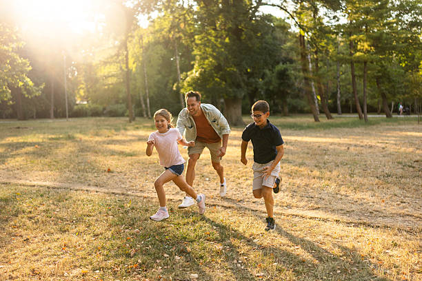 istock Father and Two Kids Running Together Outdoors in a Park Setting 2230322149