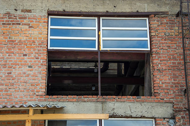istock Large window opening in an unfinished brick wall reflects the sky, showcasing ongoing construction in an urban setting 2230325389