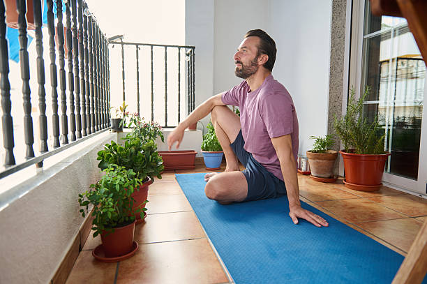 istock Man Practicing Yoga Poses on Balcony Surrounded by Green Plants 2230327397