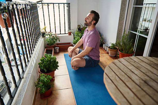 Man Practicing Meditation Yoga on Balcony Surrounded by Plants