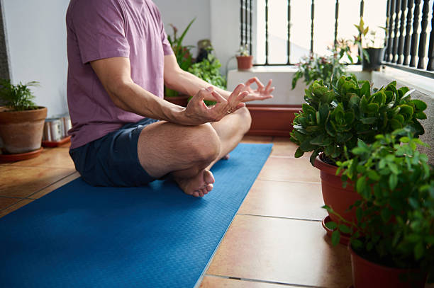 istock Man Practicing Yoga on a Balcony Surrounded by Green Plants 2230327404