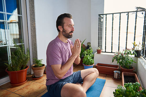 istock Man Practicing Meditation on Balcony Amidst Plants, Peaceful Outdoor Scene 2230327407