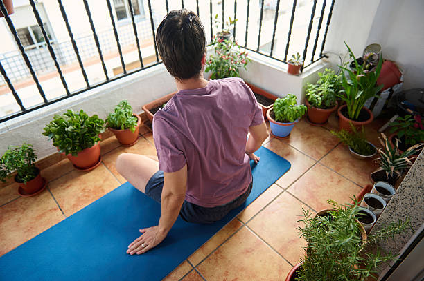 istock Male Practicing Yoga Exercise on Balcony With Plants in Relaxing Atmosphere 2230327411