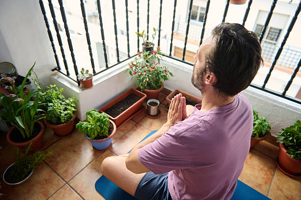istock Man Meditating on Balcony with Plants in Serene Setting 2230327414