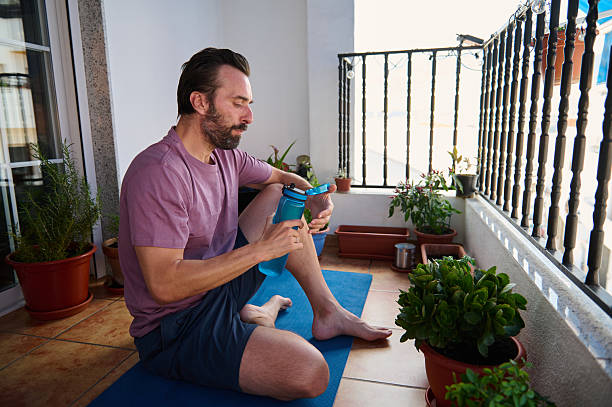 istock Man Enjoying Tea After Yoga Session on Balcony with Plants 2230327420