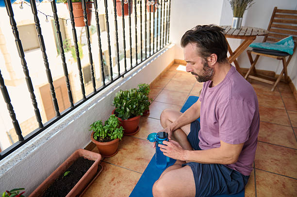 istock Man Relaxing on Balcony with Yoga Mat in Tranquil Urban Setting 2230327426