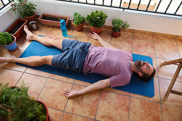 istock Man Practicing Yoga Relaxation on Balcony Surrounded by Potted Plants 2230327427