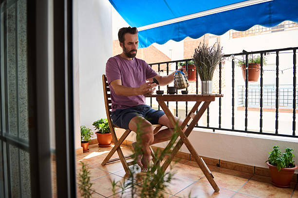 istock Man Enjoying Tea on a Cozy Balcony Surrounded by Plants 2230327455