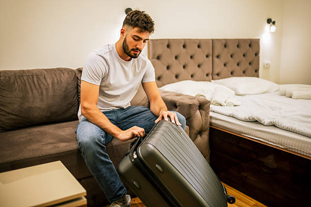 istock Man unpacking suitcase in hotel room on trip 2230329154