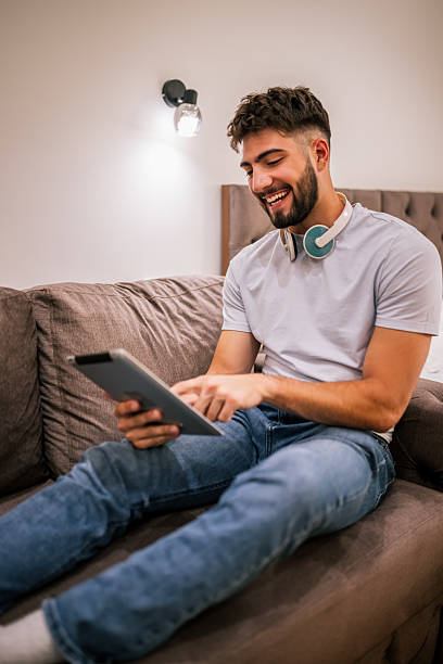 istock Man using tablet with headphones in hotel room 2230329267