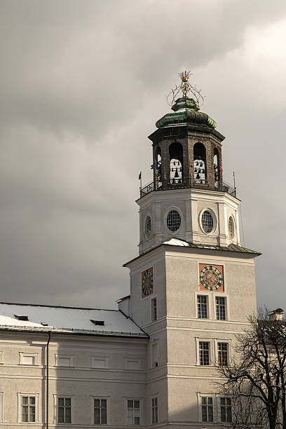 Low angle view of New Residenz bell tower against cloud sky with sunlight on the front facade, in Residence Square, Salzburg Austria.