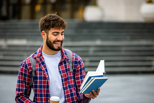 istock Male Student Reading Book and Drinking Coffee on Campus 2230333340