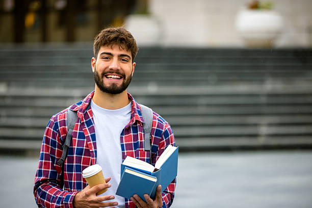 istock Male Student Reading Book and Drinking Coffee on Campus 2230333345