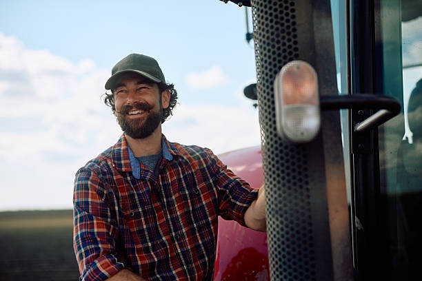 istock Happy farmer worker with a tractor working in the field. 2230335976