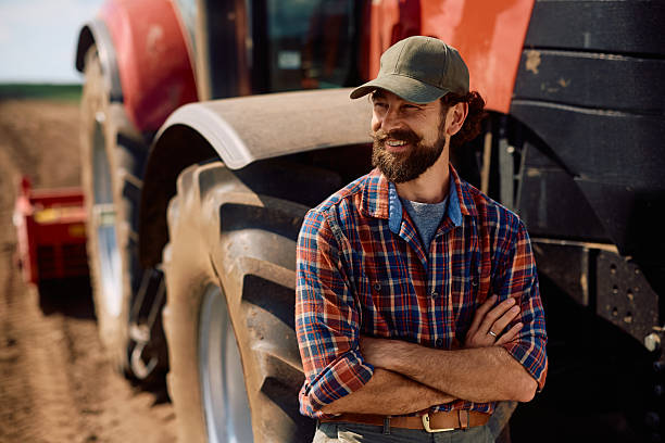 istock Confident agronomist by his tractor in the field looking away. 2230335979
