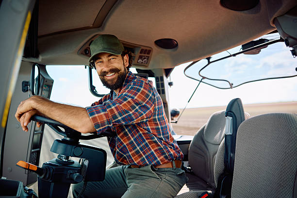 istock Happy agronomist driving tractor and looking at camera. 2230336003