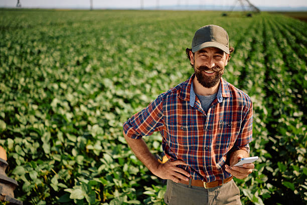 istock Happy agriculturist using cell phone while working in the field and looking at camera. 2230336142