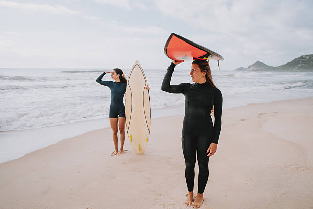 istock Two surfer friends holding surfboards over their heads 2230338601