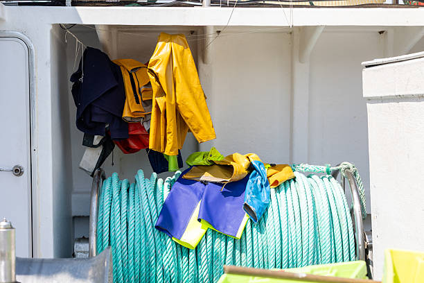 Fisherman's waterproof clothes hanging and laying on turquoise rope aboard ship