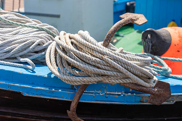 Rusty anchor and rope resting on the edge of a blue fishing boat