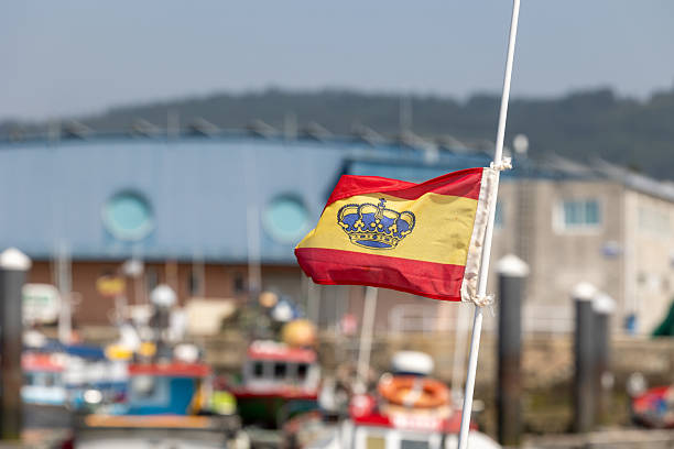 Spanish flag waving on a pole in a harbor
