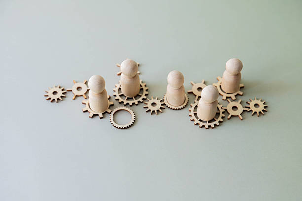 istock A conceptual image with wooden figures standing on interconnected gears. Teamwork 2230341784