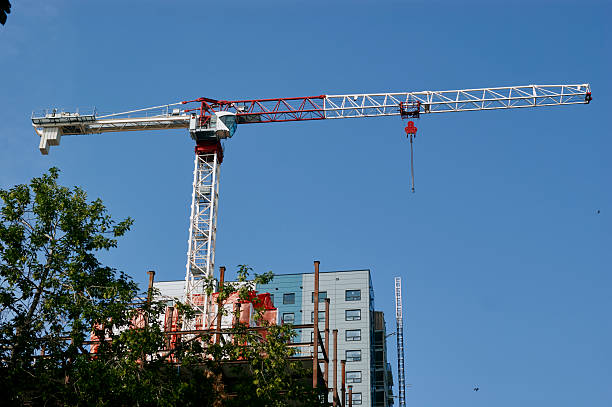 Steel frame high-rise building under construction with a tower crane against blue sky in Saskatchewan, Canada.