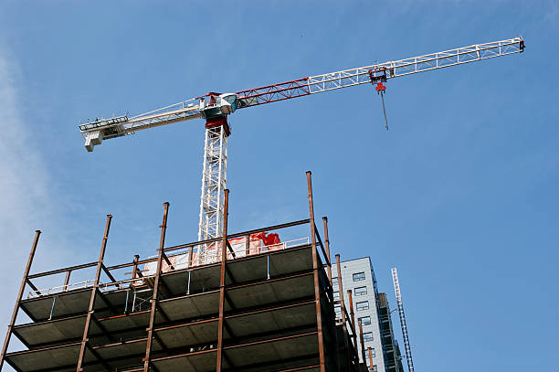 Steel frame high-rise building under construction with a tower crane against blue sky in Saskatchewan, Canada.