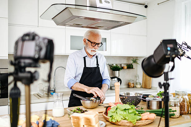 istock Senior chef recording cooking show in kitchen: preparing healthy dish 2230342638
