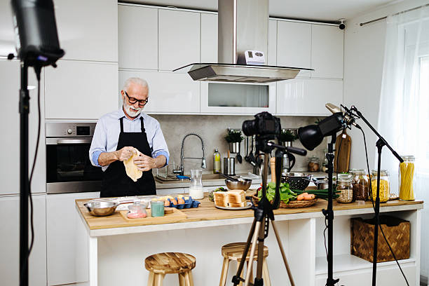 istock Senior chef kneading dough while recording cooking show in kitchen 2230342732