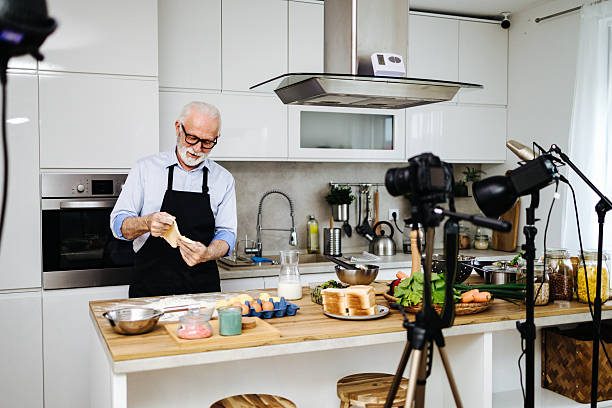 istock Senior chef kneading dough while recording cooking show in kitchen 2230342735