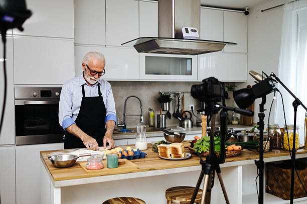 istock Senior chef recording cooking show in kitchen studio: kneading dough 2230342740