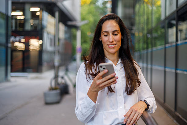 istock Smiling businesswoman enjoying a break from work while using her smartphone on a bustling city street, embodying modern urban lifestyle 2230344545
