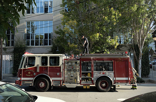 Los Angeles, California - December 18, 2024: Bright red fire truck navigating Venice Boulevard, surrounded by palm trees and urban scenery under a clear blue sky.