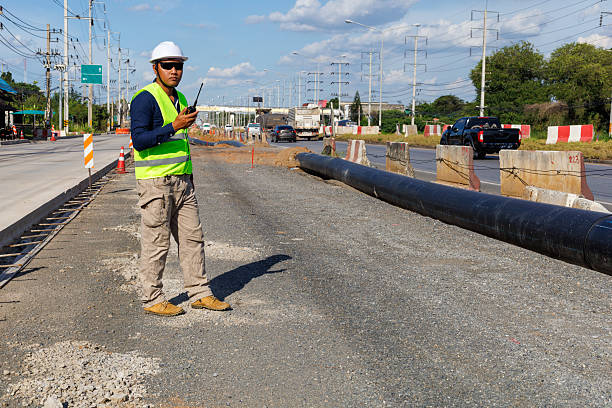 An engineer at a large road construction site. Traffic cones and traffic barriers mark the area in a large infrastructure project. Construction supervisor, work, road structure.