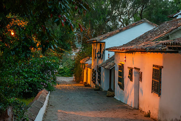 A picturesque view of a cobblestone street in Villa de Leyva, Boyaca, showcasing traditional white houses illuminated by warm light.