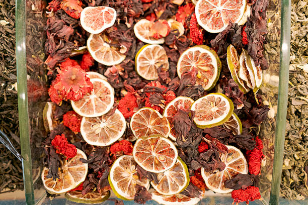 Glass bowl filled with dried fruit and flowers. The fruit includes oranges and lemons. The bowl is placed on a table
